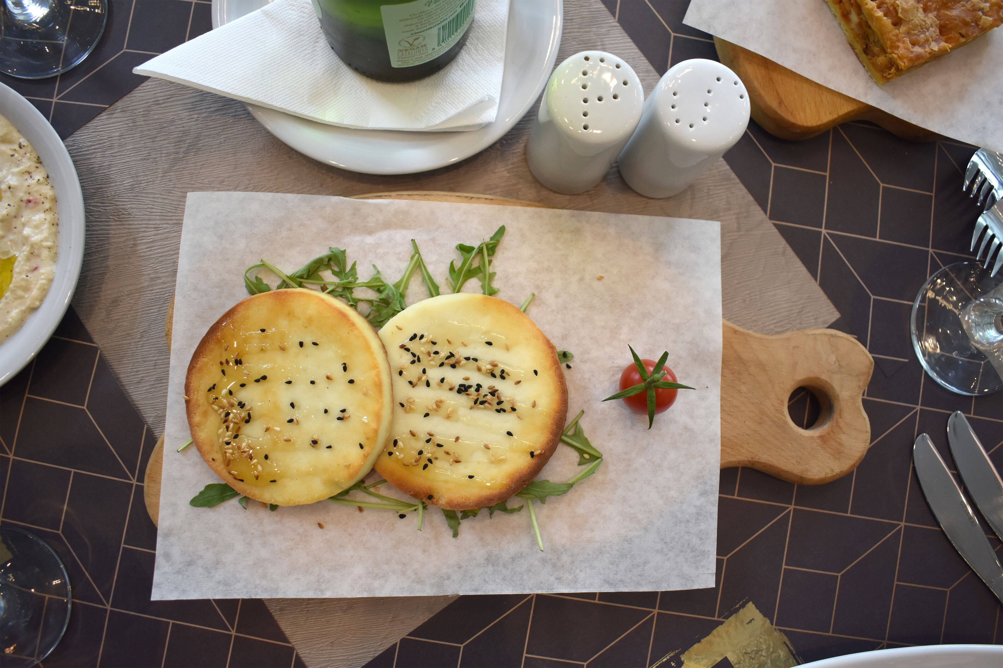 Une table avec une assiette de nourriture, une bouteille, des salières et des poivrières, ainsi que des couverts.