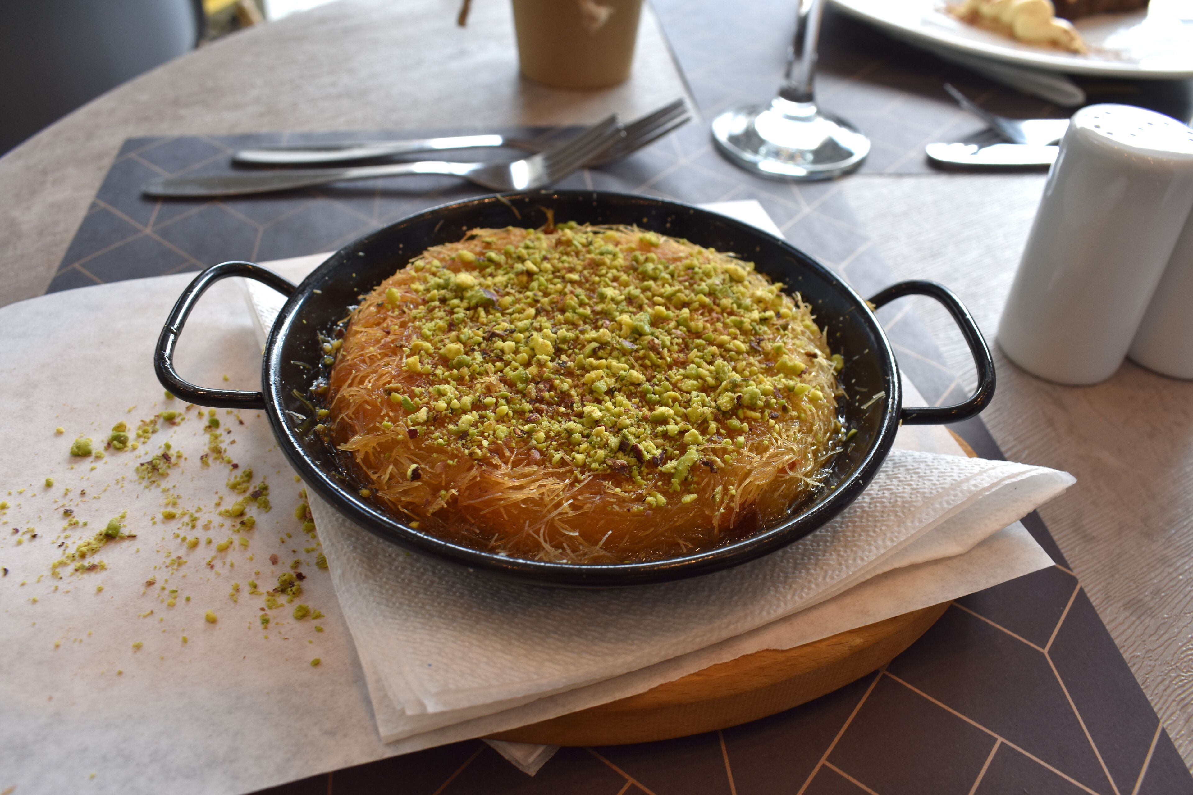 Un plat rond de baklava est posé sur une table, avec une serviette et des salières et poivrières à proximité.