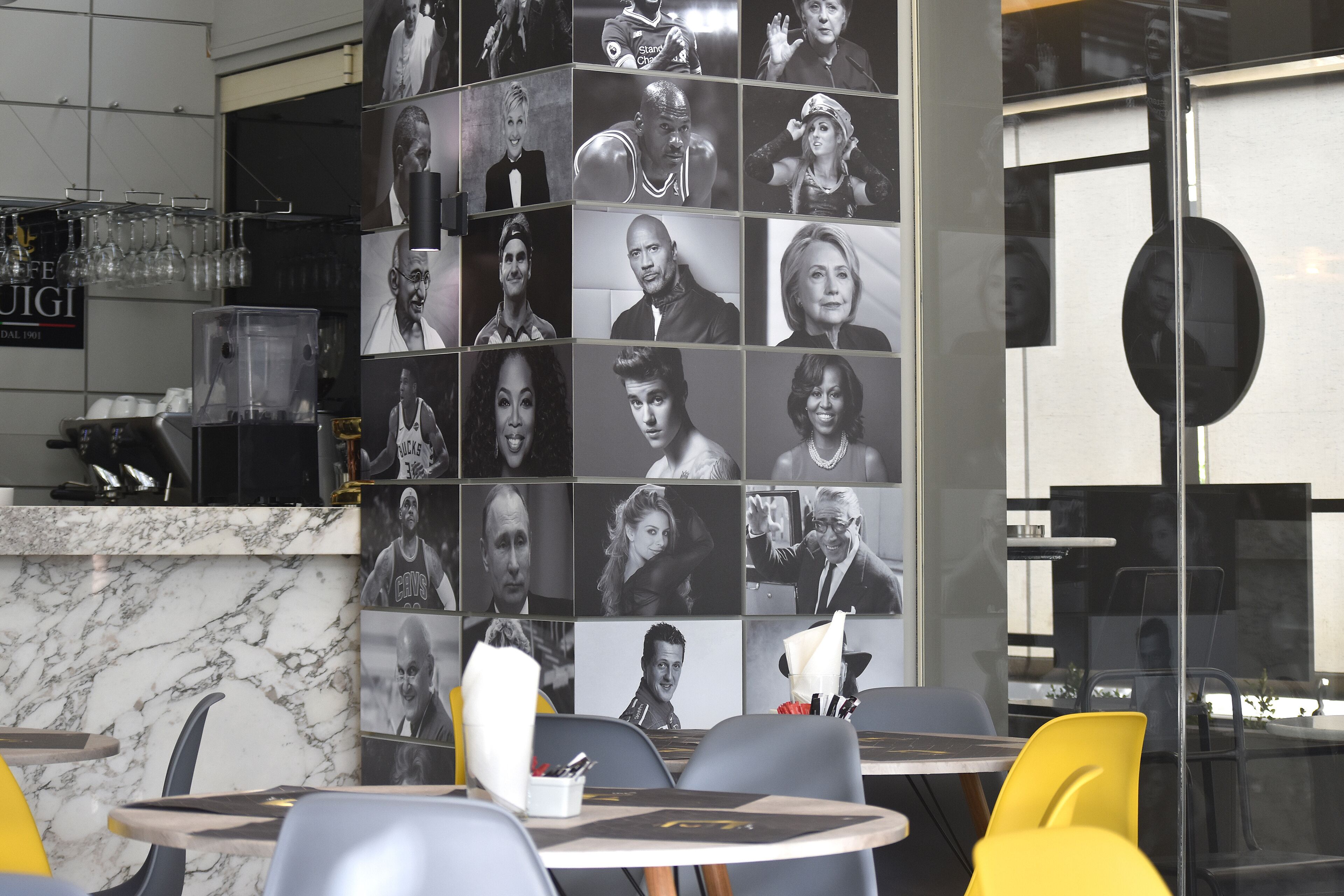 A restaurant interior with a wall of black and white photos, marble countertops, and modern seating.