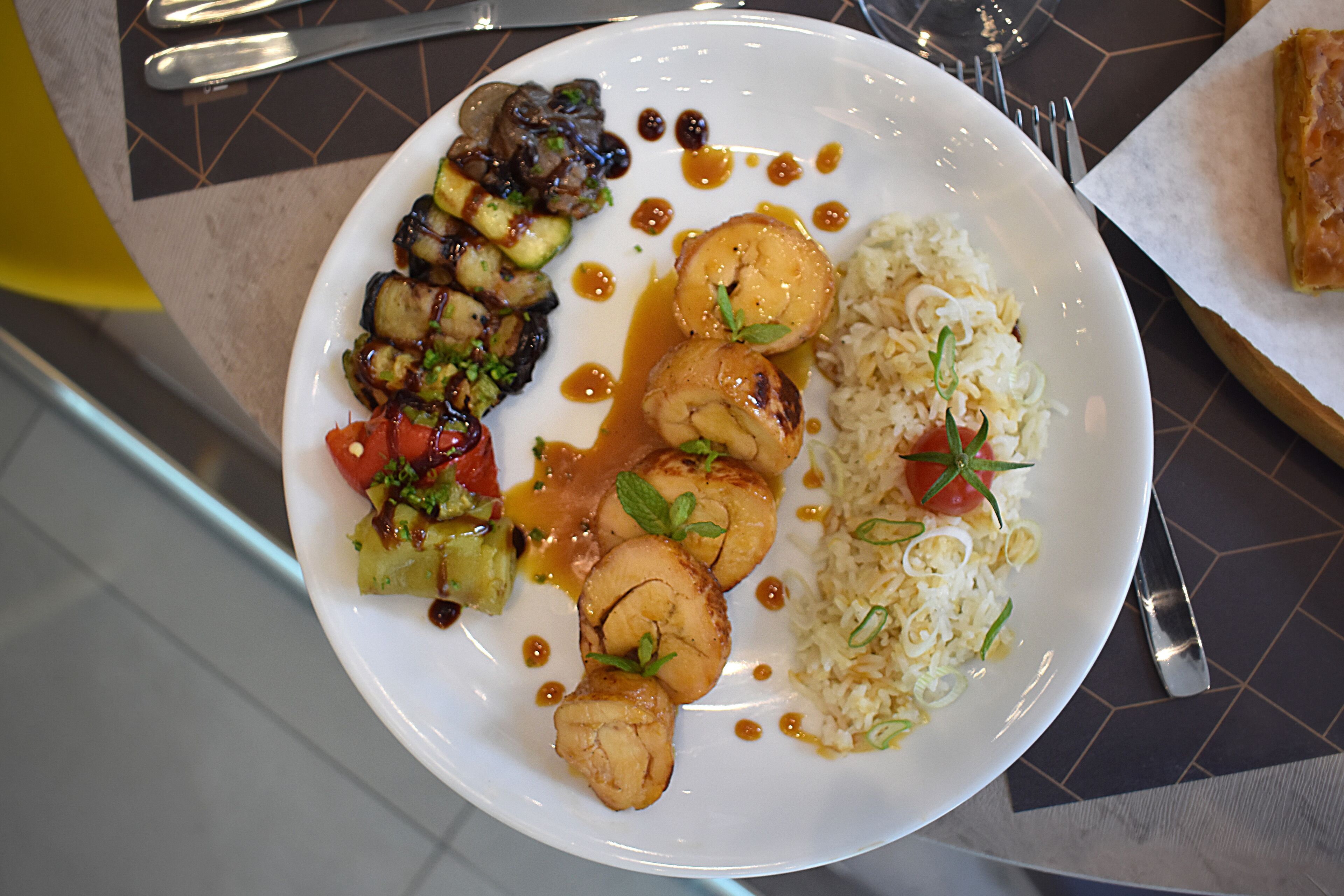 Une assiette de nourriture contenant divers éléments, notamment du riz, des légumes et, éventuellement, de la viande, le tout servi dans une assiette blanche.