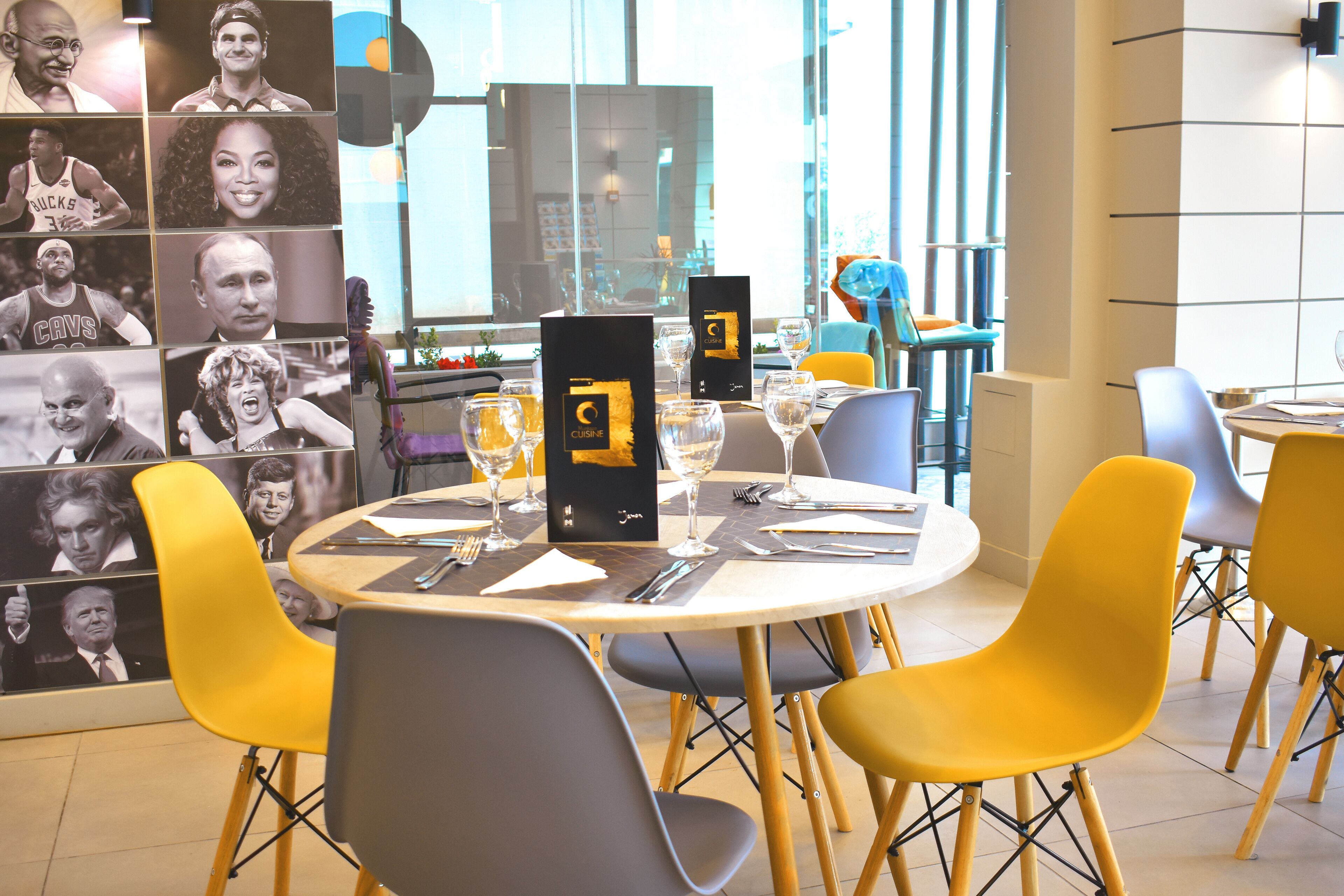 A dining area with round tables, yellow chairs, and black menu stands.