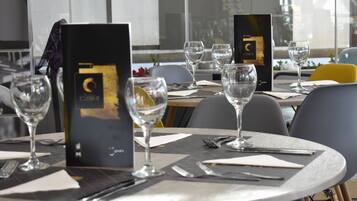 Un ambiente de restaurante con mesas preparadas para comer, menús y copas de vino.