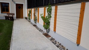 Relax in the serene outdoor space adjacent to the building, featuring a paved walkway and a comfortable bench.