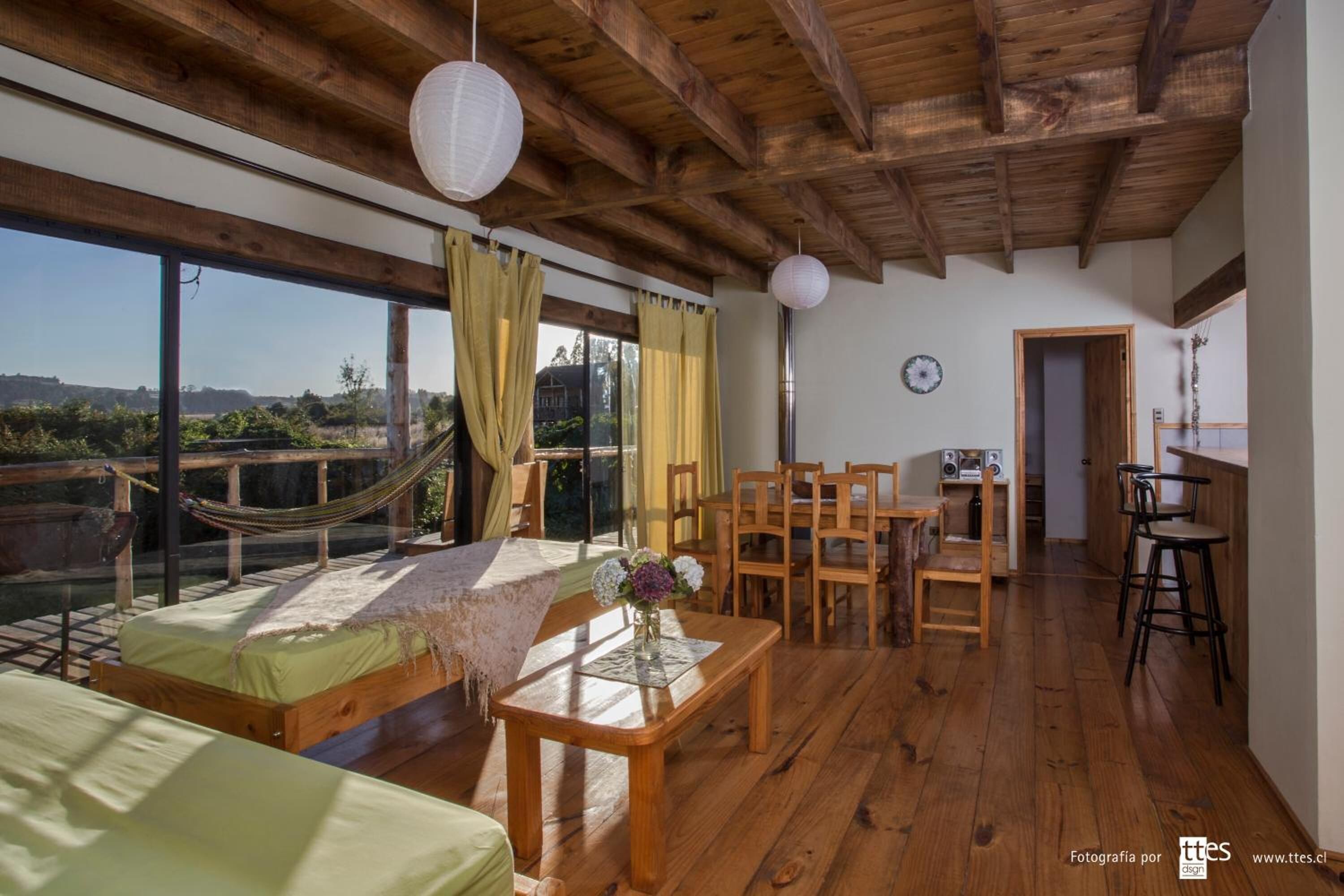 A spacious room with a large window, wooden furniture, and a hammock.