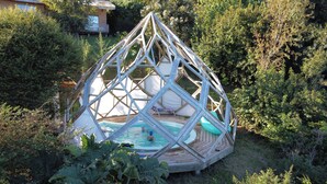 A geodesic dome structure with a pool in the center, surrounded by dense greenery. - Antuquelen Lodge Cabañas (Frutillar)