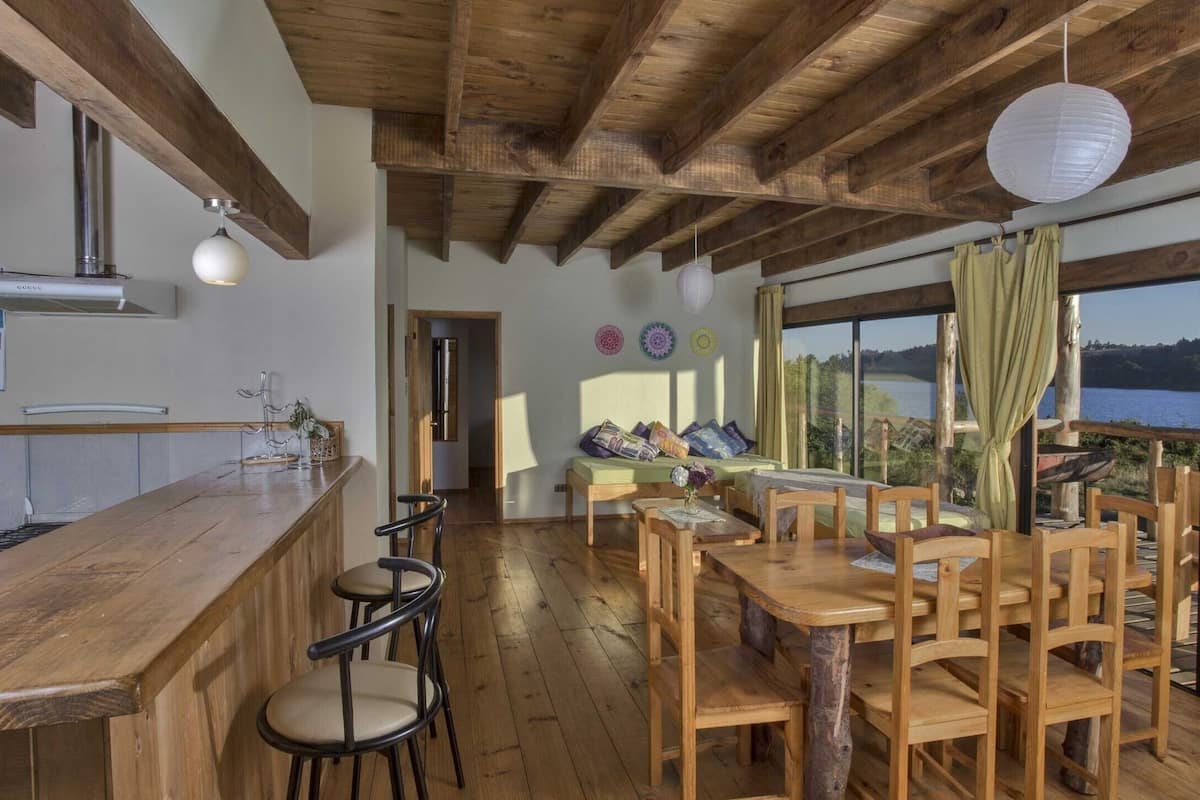 A rustic interior with a wooden dining table, chairs, and a bar area.