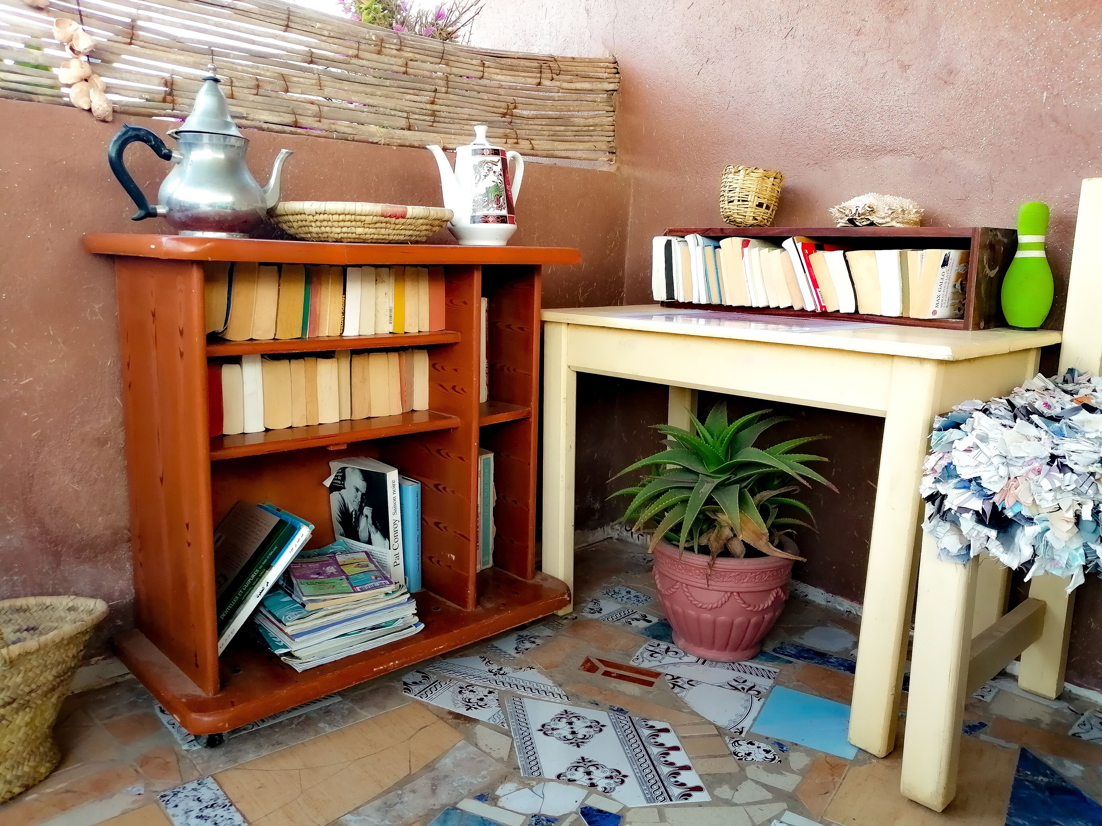 Un rincón acogedor para leer con una estantería de madera, una mesita y una planta en maceta.