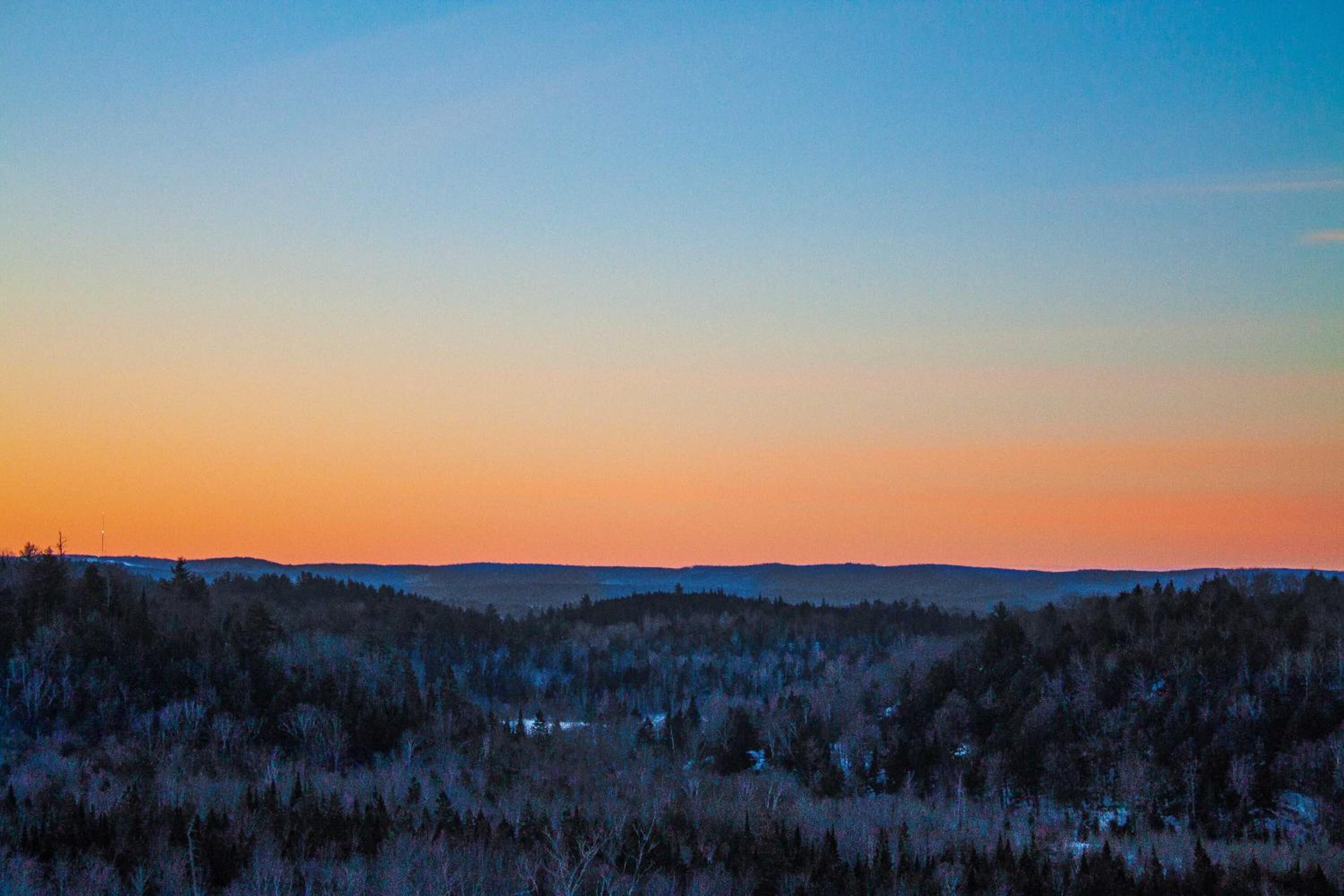 Un paysage boisé, avec un ciel dégagé au crépuscule.