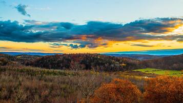 A mountainous landscape with autumn foliage and a sunset sky.