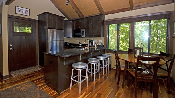 A modern kitchen with a central island, stainless steel appliances, and wooden flooring.