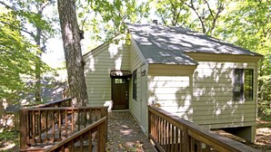 A small cabin with a wooden deck and a door leading to the interior.