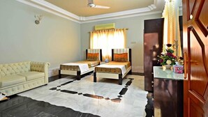 A hotel room with two beds, a sofa, a marble floor, a ceiling fan, and a door with a decorative panel. - BlueSky Guest House (Karachi)