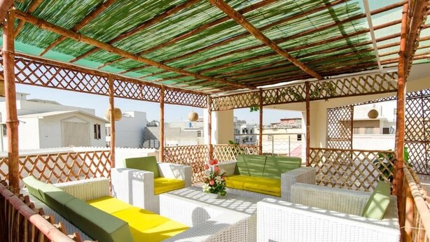 A covered outdoor seating area with wicker furniture and a bamboo lattice structure. - BlueSky Guest House (Karachi)