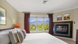 A hotel room with a large bed, a fireplace, a window with a mountain view, and two framed pictures on the wall. - Topnotch Overlook Resort Home with Mansfield views (Stowe)