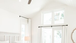 Una camera da letto con un letto, una ventola a soffitto, una finestra con tende e vista sull'esterno.