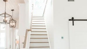 Una scala con gradini in legno e pareti bianche, che conduce a una porta con maniglia nera.