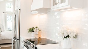 Una cucina moderna con mobili bianchi, elettrodomestici in acciaio inossidabile e illuminazione decorativa.