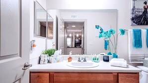 A modern bathroom with a white sink, wooden vanity, and a large mirror.