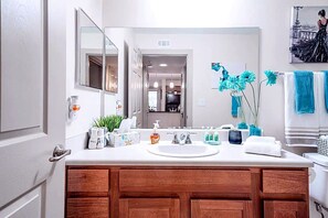 A modern bathroom with a white sink, wooden vanity, and a large mirror.