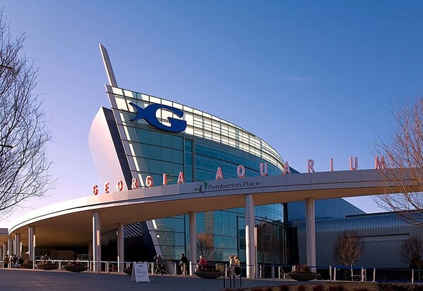 Un bâtiment moderne doté d’une grande façade en verre et d’un logo en forme de « X » bien visible.
