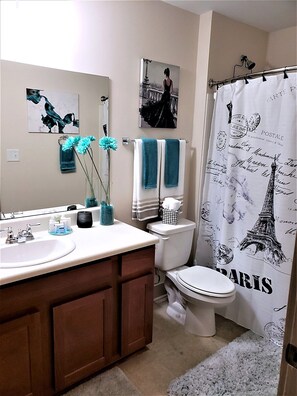 A bathroom with a white sink, a mirror, a toilet, and a shower curtain with Parisian designs. - Walk to Aquarium & Stadiums · Free Parking (Atlanta)