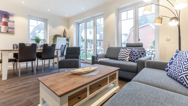 Una sala de estar moderna con comedor, ventanas amplias y vista al exterior.