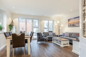 A modern living room with a dining area, large windows, and a view of the outside. - House Jensen 1, Germany (List)