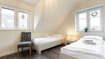A bedroom with a loft bed, a single bed, a chair, and two bedside tables with lamps.
