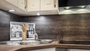 Una cocina moderna con armarios de madera oscura, electrodomésticos de acero inoxidable y una obra de arte con tema de café.