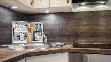 A modern kitchen with dark wooden cabinetry, stainless steel appliances, and a coffee-themed wall art.