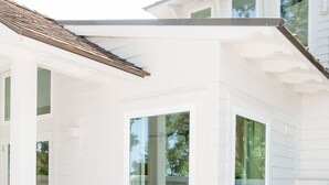 Ein modernes Haus mit Schwimmbad, großen Fenstern und einer überdachten Terrasse.