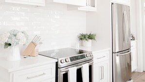 Eine moderne Küche mit weißen Schränken, einem Edelstahlkühlschrank und einem schwarzen Backofen.