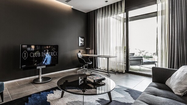 A modern living room with a flat-screen TV, a glass coffee table, and a sofa.
