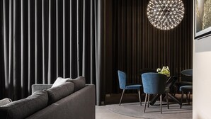 A modern living room with a sofa, blue chairs, and a dining table.