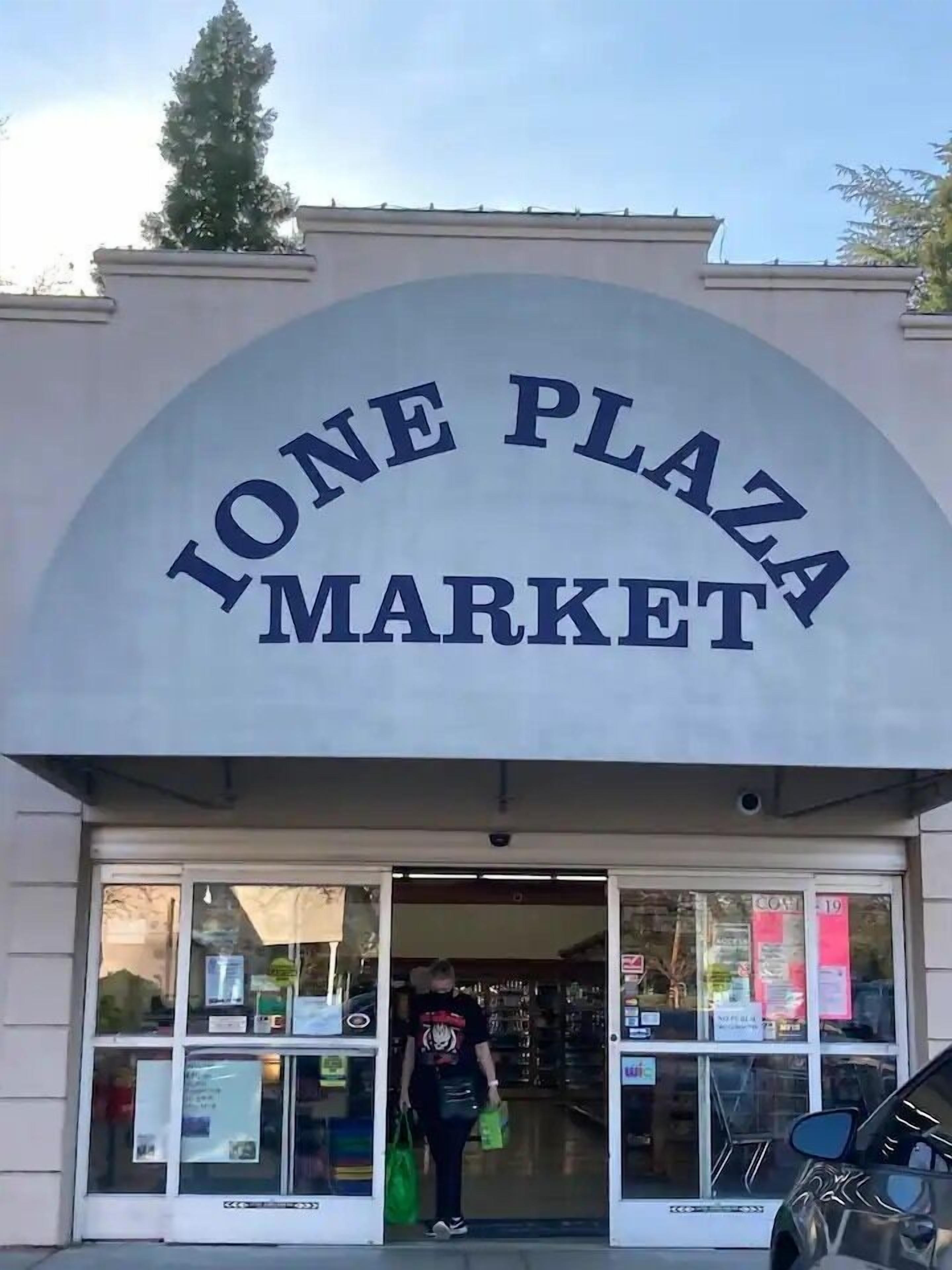 The entrance to Ione Plaza Market with a clear archway and a person entering.