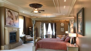 A spacious bedroom with a large bed, a fireplace, and a ceiling fan. - Wildflower Ranch Inn (Springfield)