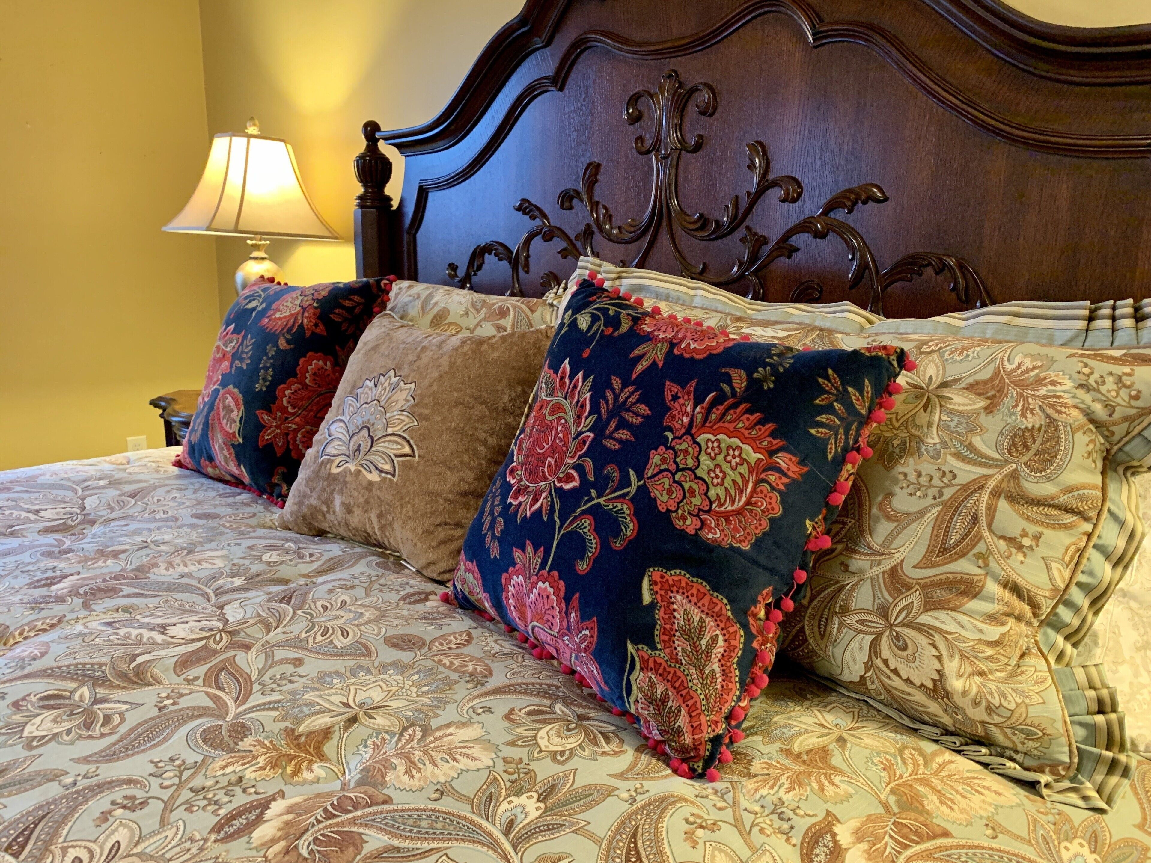 A bed with ornate headboard and floral-patterned bedding.