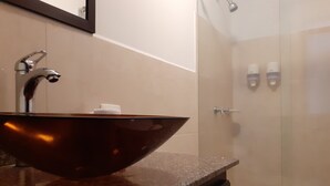 A bathroom with a brown ceramic sink, a mirror, and a shower area. - Gran Hotel Coral (Popayán)