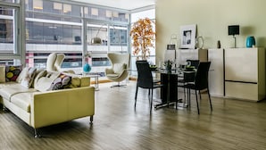 Un salon moderne comprenant un canapé, des fauteuils, une table à manger et un coin cuisine.