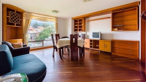 A spacious living area with a dining table, chairs, and a sofa. There is a television and wooden cabinets. - La Macarena 2001 (Bogotá)