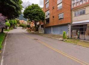 A residential street with brick buildings, a tree-lined sidewalk, and a parked car. - La Macarena 2001 (Bogotá)