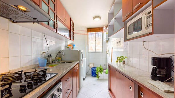 A kitchen with a gas stove, microwave, and cabinets. - La Macarena 2001 (Bogotá)