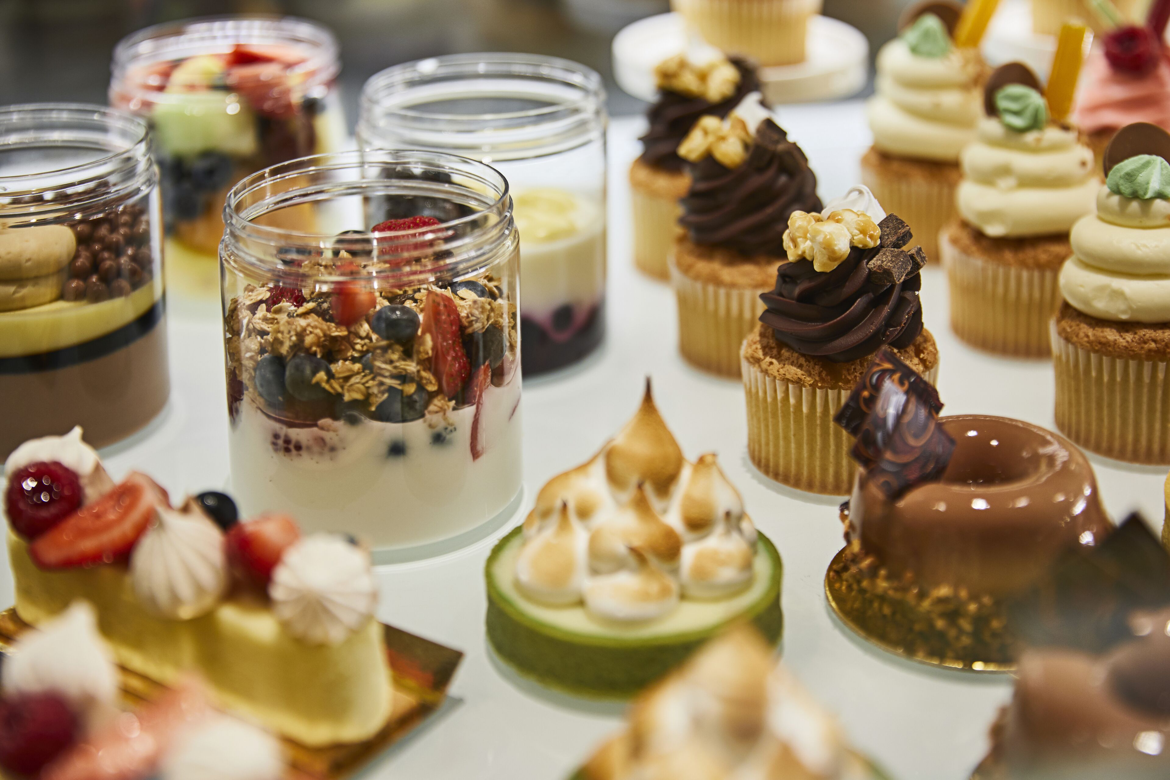 A variety of desserts including cakes, cupcakes, and parfaits.