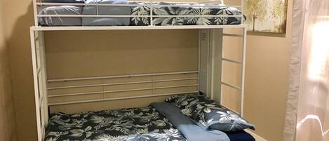 A bunk bed with floral bedding, a wooden headboard, and a painting on the wall.