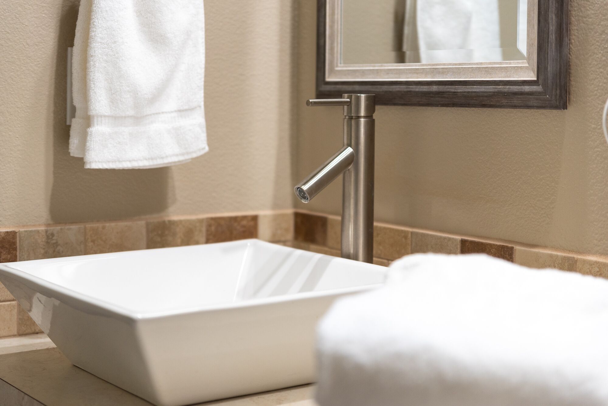A bathroom with a white sink, a towel hanging on the wall, and a mirror.