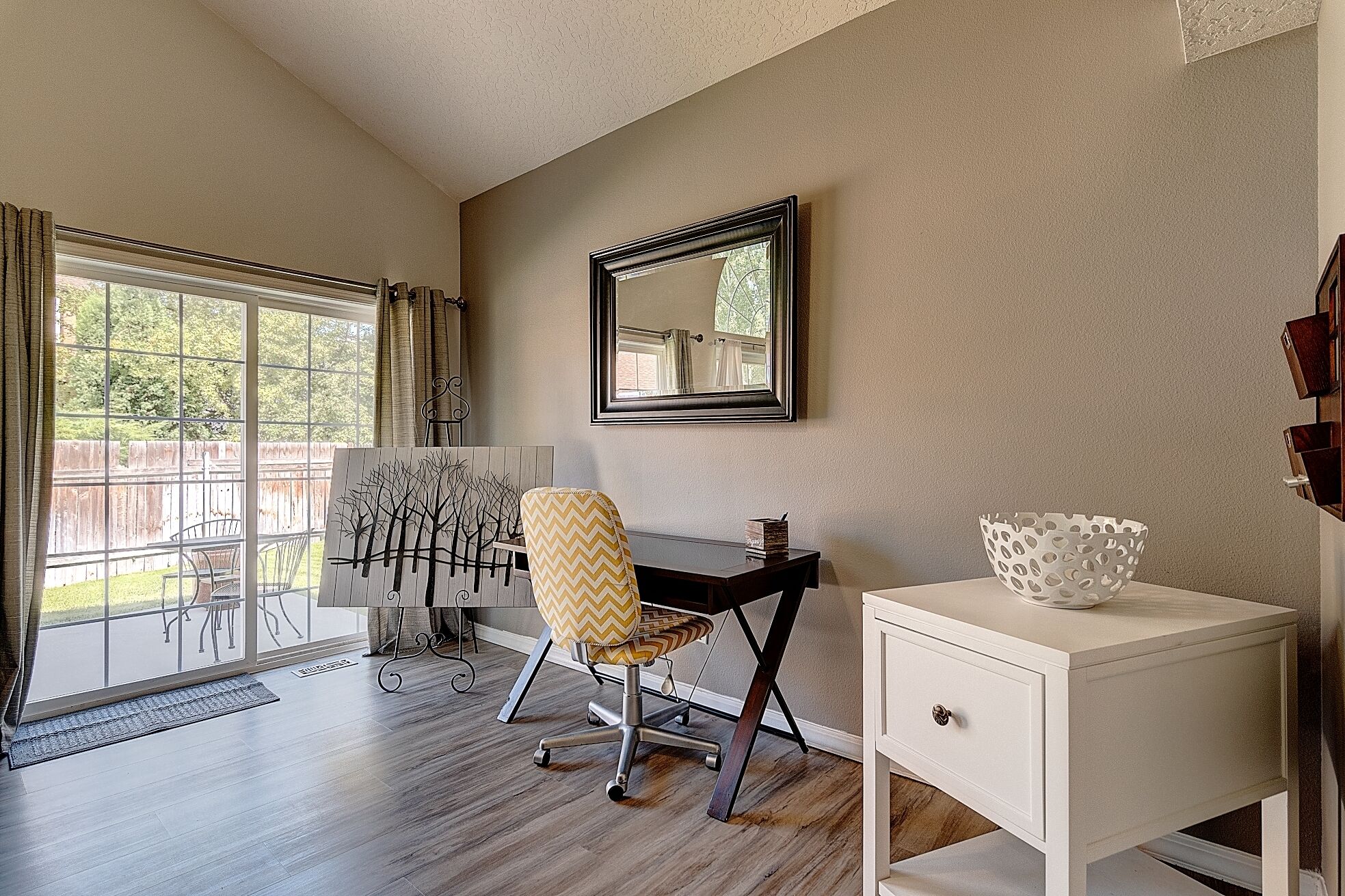 A room with a desk, chair, and a white console table.