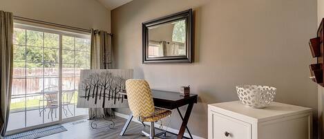 A room with a desk, chair, and a white console table.
