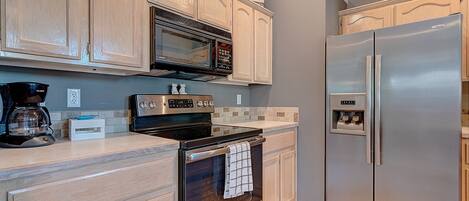 A kitchen with wooden cabinets, a stainless steel refrigerator, a microwave, and a coffee maker.