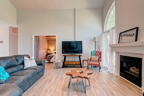 Een moderne woonkamer met een bank, een salontafel, een televisietoestel en een open haard.