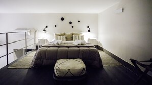 Un dormitorio ordenado con cama, lámparas de noche, una mesita y un banco.